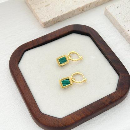 Gold hoop earrings with rich green malachite pendants and subtle statement silhouette