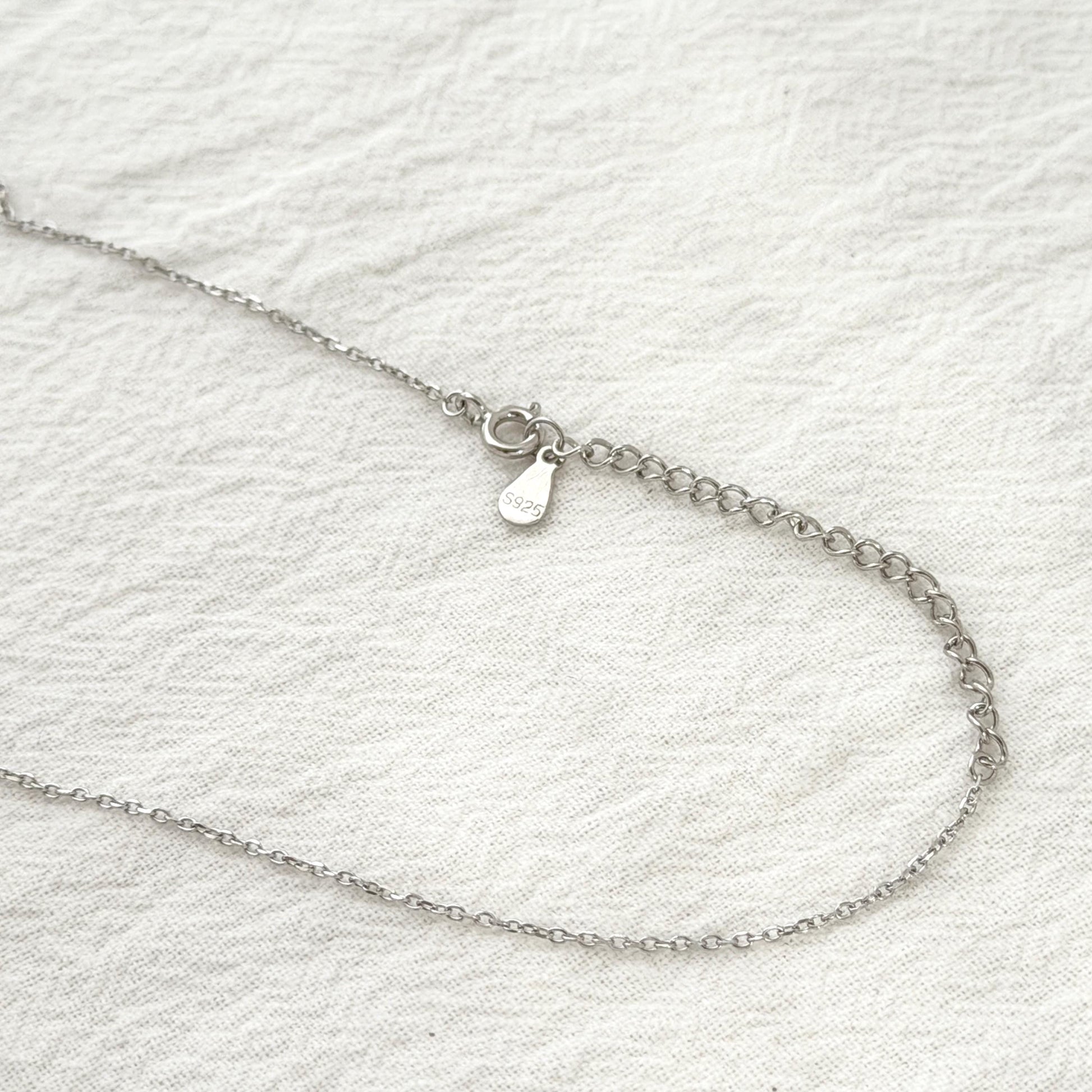 Long layering necklace with sculptural silver pendant and clean minimalist aesthetic