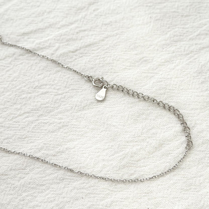 Long layering necklace with sculptural silver pendant and clean minimalist aesthetic