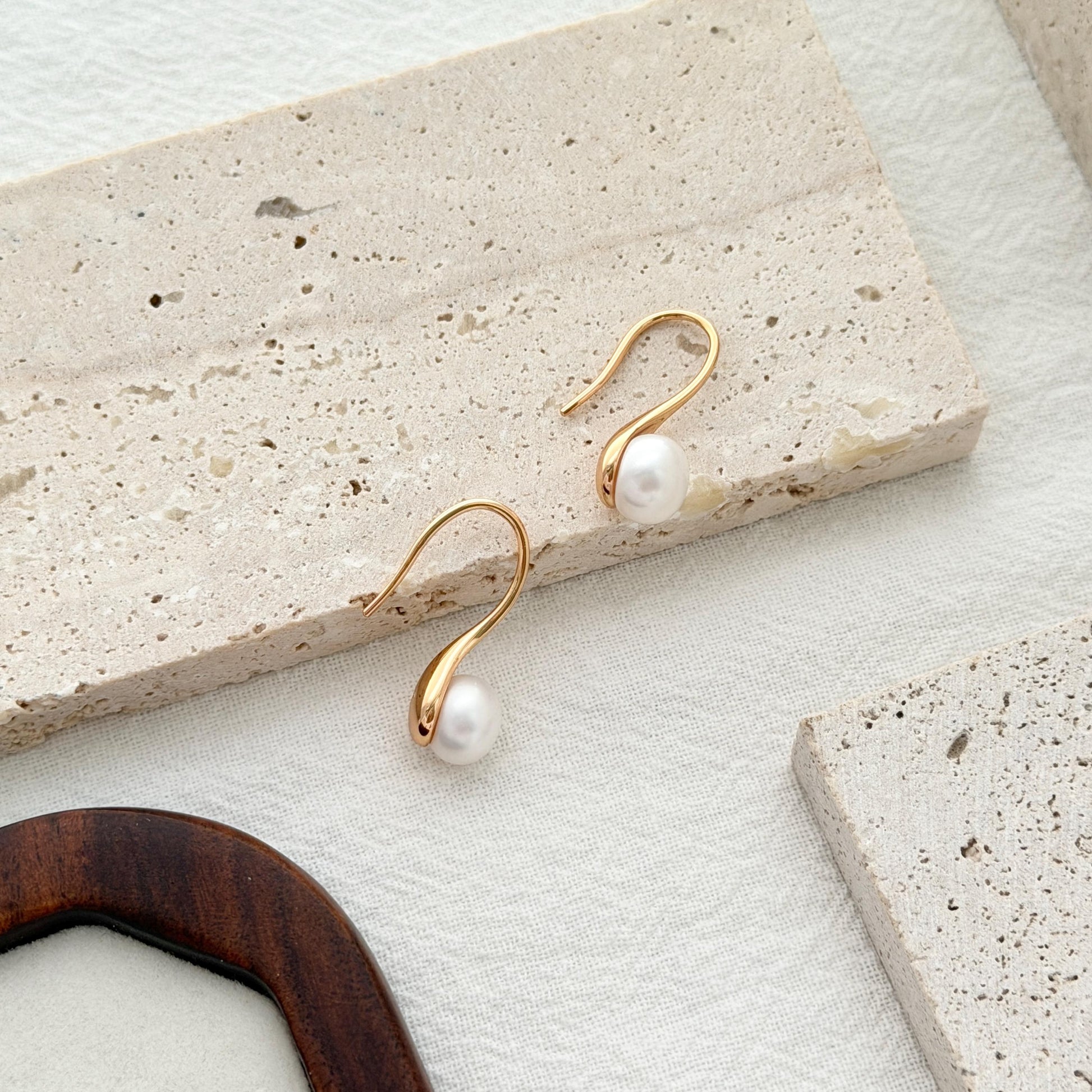 Minimal gold pearl hook earrings with modern curved silhouette and luminous freshwater pearls