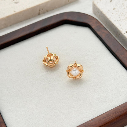Statement pearl flower earrings displayed on a dark wooden jewelry tray with a minimalist background.
