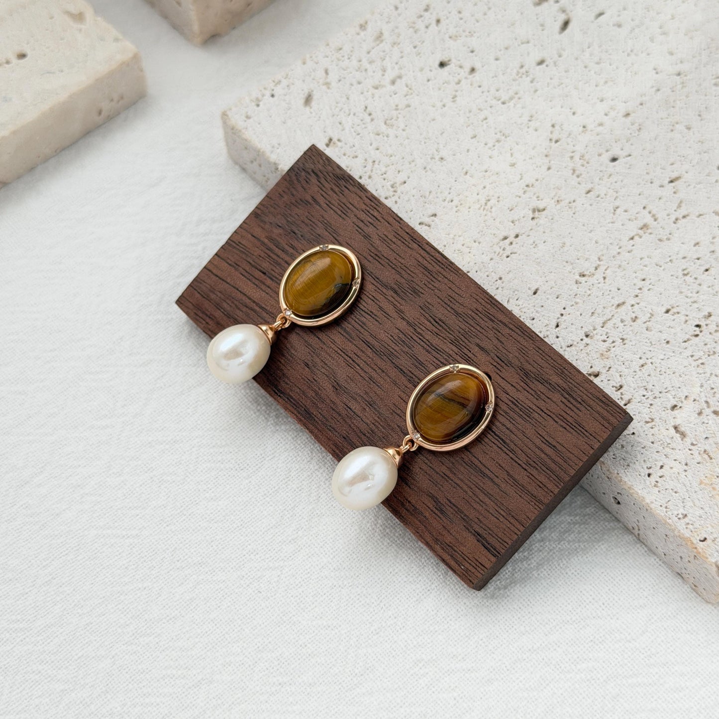 Brown gemstone and pearl dangle earrings featuring oval tiger’s eye stones and crystal accents.
