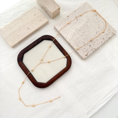 Dainty gold Y necklace with small bead details and a delicate lariat-style drop.