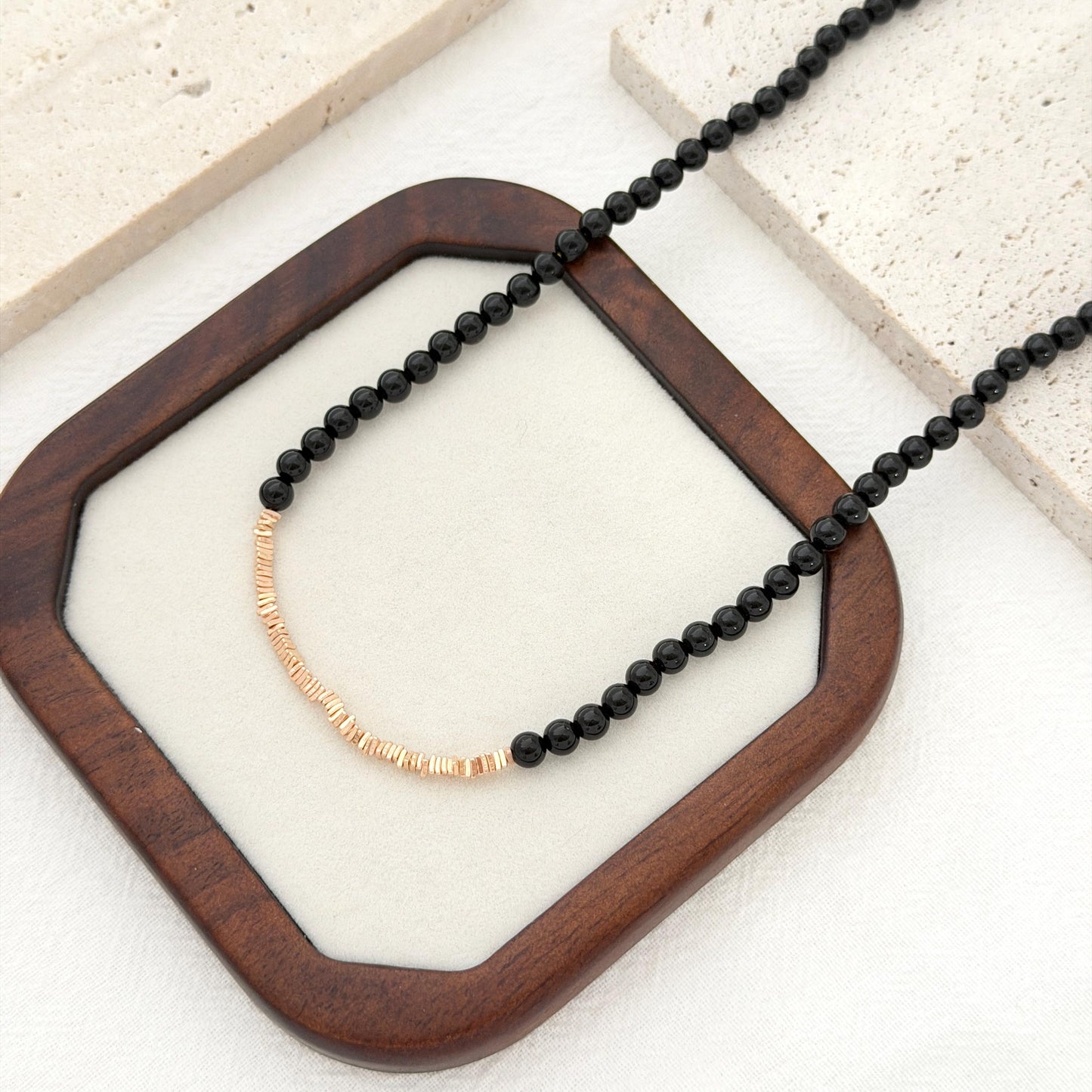 Minimal black beaded choker necklace with gold accents and an adjustable chain.