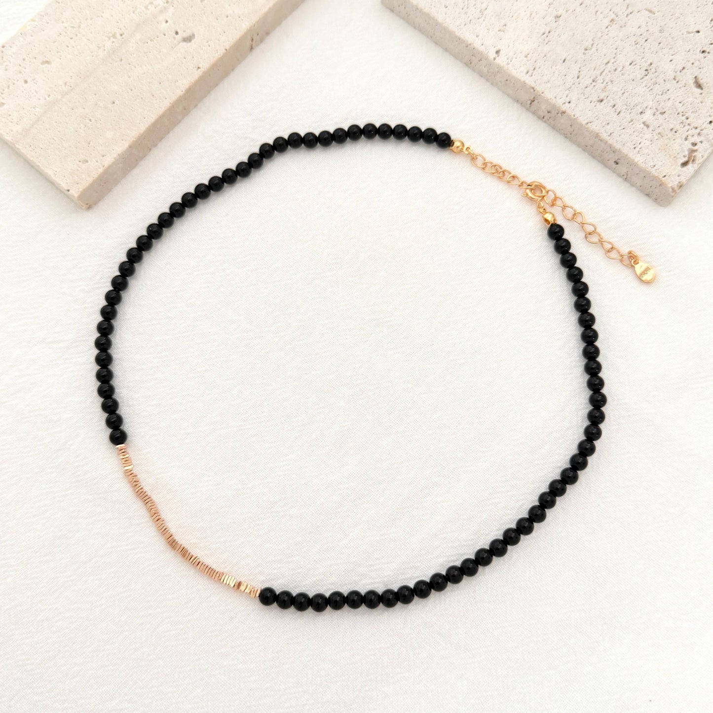 Dainty black onyx choker featuring polished beads, gold accents, and an adjustable extender.