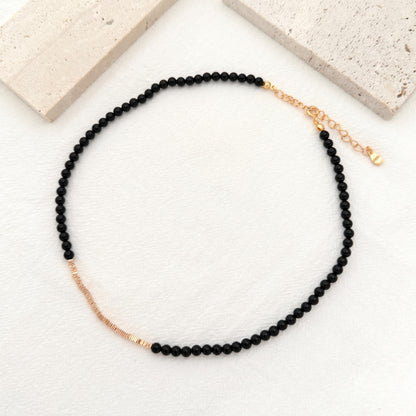 Dainty black onyx choker featuring polished beads, gold accents, and an adjustable extender.