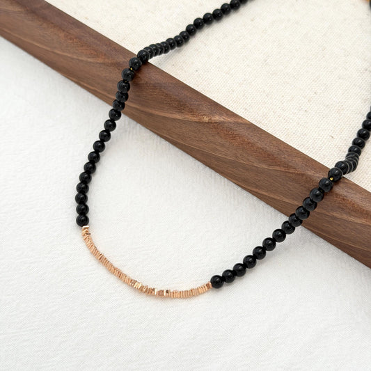 Black beaded necklace with gold accents and adjustable extender