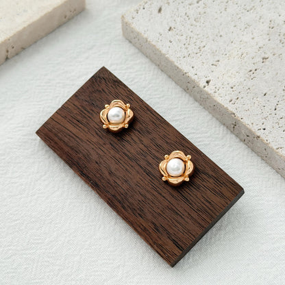 Close-up of gold floral earrings featuring luminous natural freshwater pearls in the center.