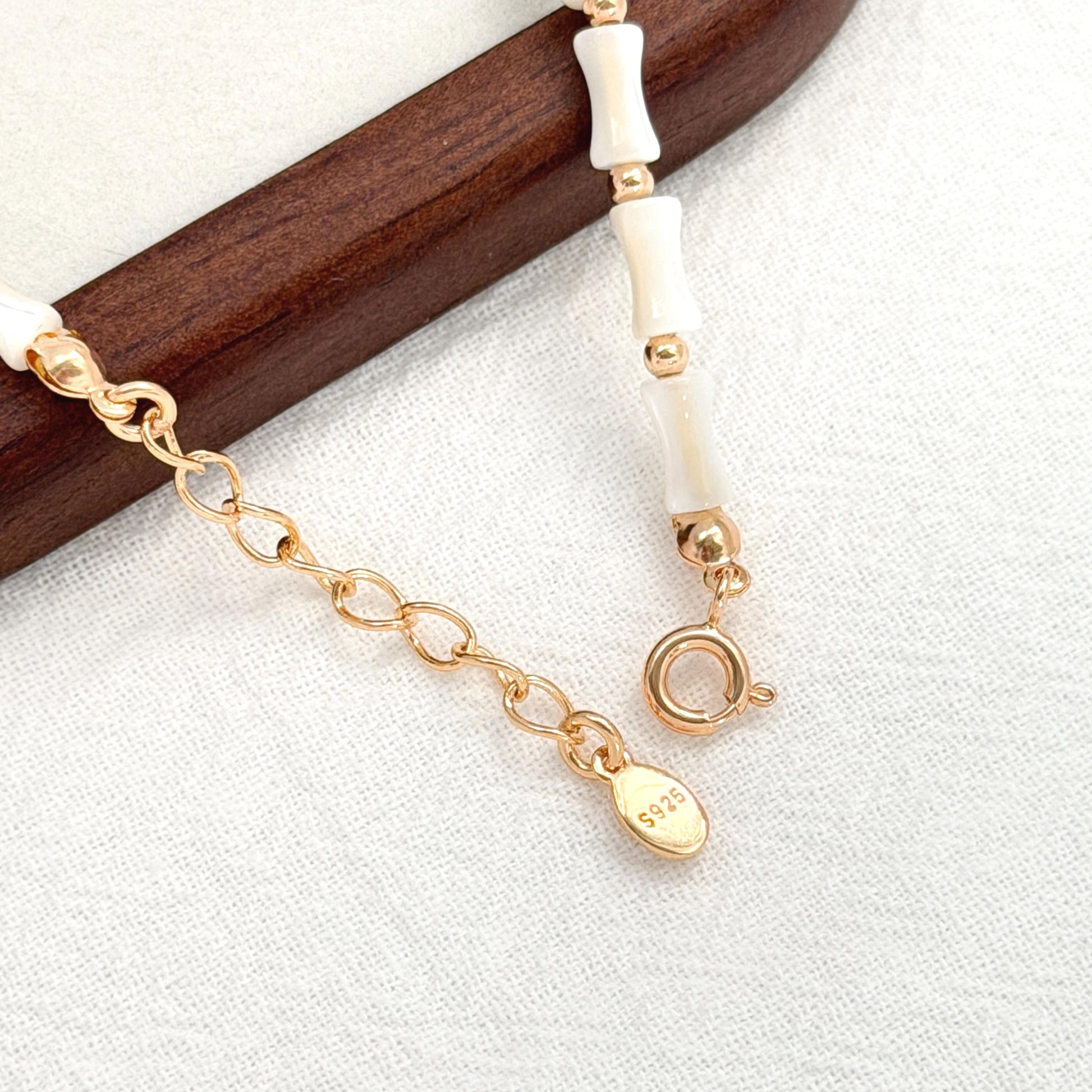 Dainty shell bracelet featuring ivory white shell beads, small gold beads, and a gold extender chain.