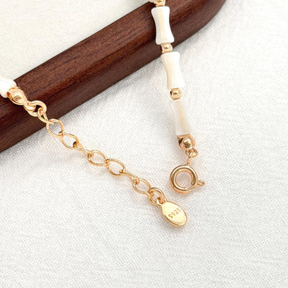 Dainty shell bracelet featuring ivory white shell beads, small gold beads, and a gold extender chain.