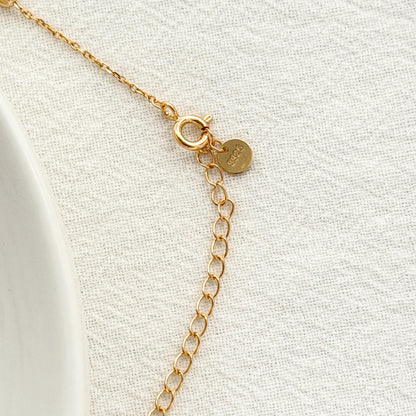 Delicate gold lariat necklace with subtle station beads and a soft minimalist design.