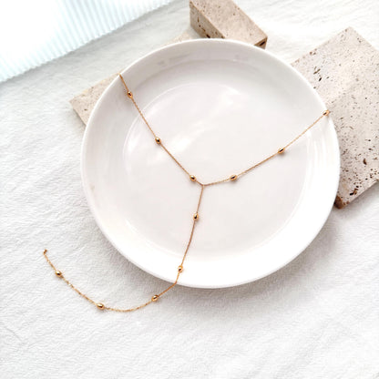 Elegant gold bead chain necklace with a Y-shaped drop, perfect for layering or evening wear.