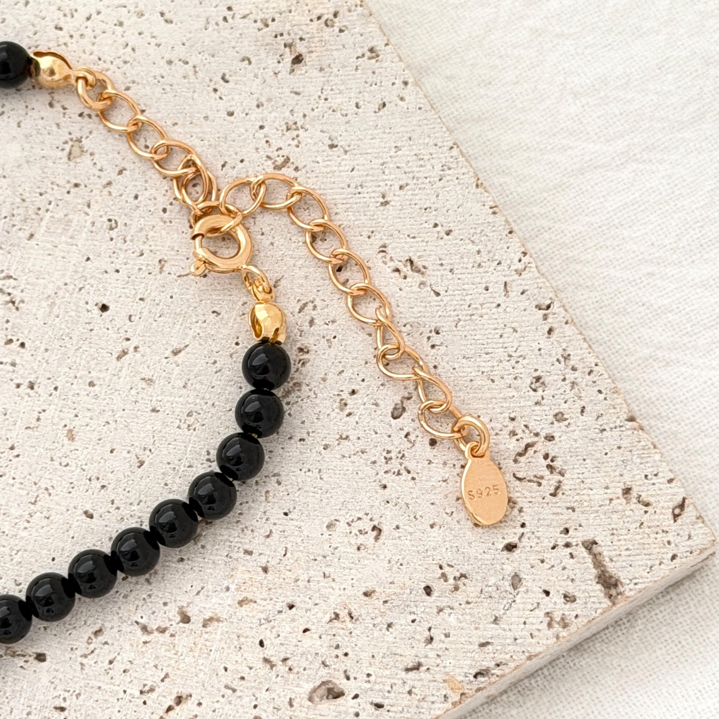 Elegant black bead necklace with subtle gold details, styled on a neutral jewelry background.