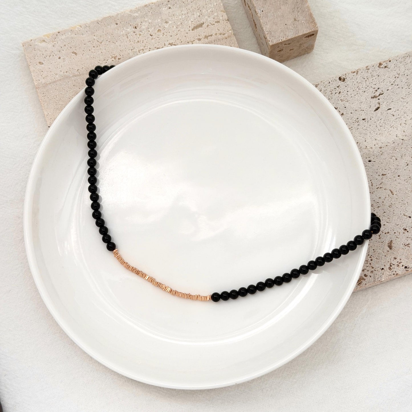 Black gemstone beaded necklace with gold detail, perfect for layering or evening wear.